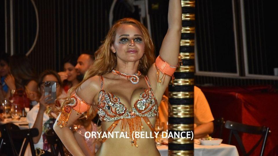 Danzatrice del ventre in costume dorato ricamato tra gli ospiti a uno spettacolo serale di Istanbul