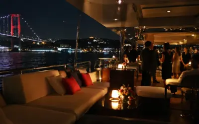 Bosphorus dinner cruise at night with a candlelit deck lounge and the illuminated 15 July Martyrs Bridge behind