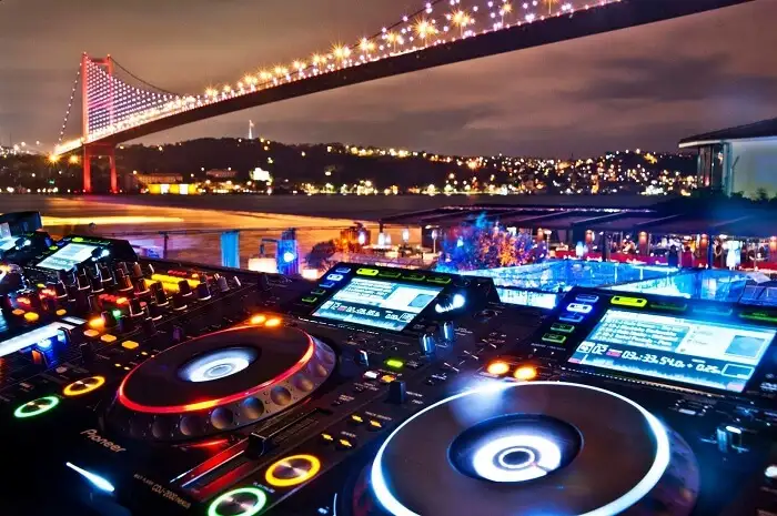 Cabine de DJ et table de mixage éclairées pendant le set d'après-spectacle sur une croisière nocturne du Bosphore