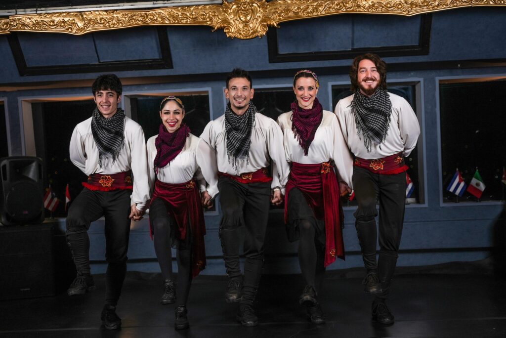 Convives et danseurs se tenant par les petits doigts dans une ligne de halay pendant le spectacle d'une croisière dîner sur le Bosphore
