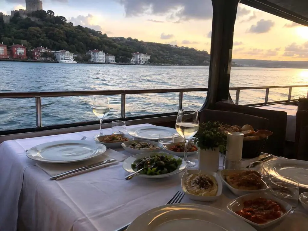 Bosphorus dinner cruise table with sunset view of Rumeli Fortress